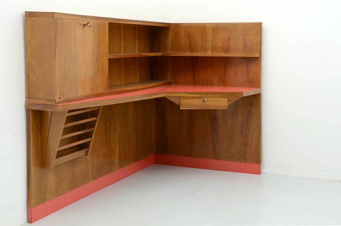 Parete arredata angolare con scomparto chiuso, portariviste, ripiani e piano scrittoio con formica rossa in perfetto stato di conservazione. Italia 1950ca.