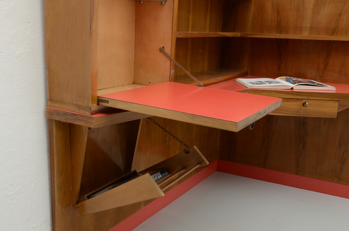 Parete arredata angolare con scomparto chiuso, portariviste, ripiani e piano scrittoio con formica rossa