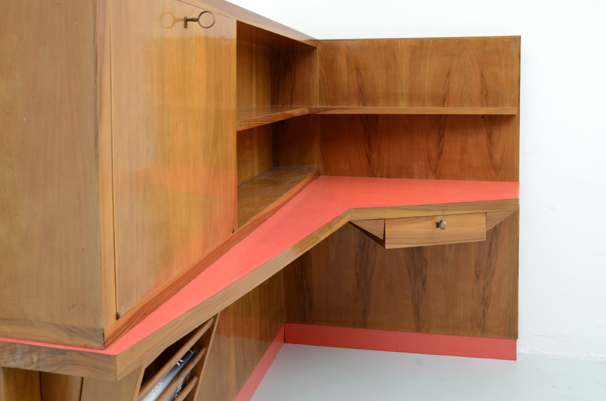 Parete arredata angolare con scomparto chiuso, portariviste, ripiani e piano scrittoio con formica rossa