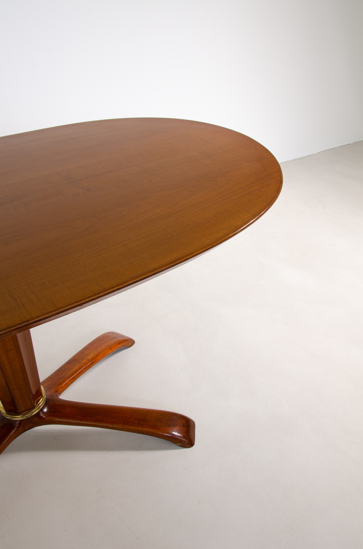 Osvaldo Borsani, tavolo in ciliegio con piano ovale, base a quattro razze e colonna centrale con anello in bronzo, 1950ca.