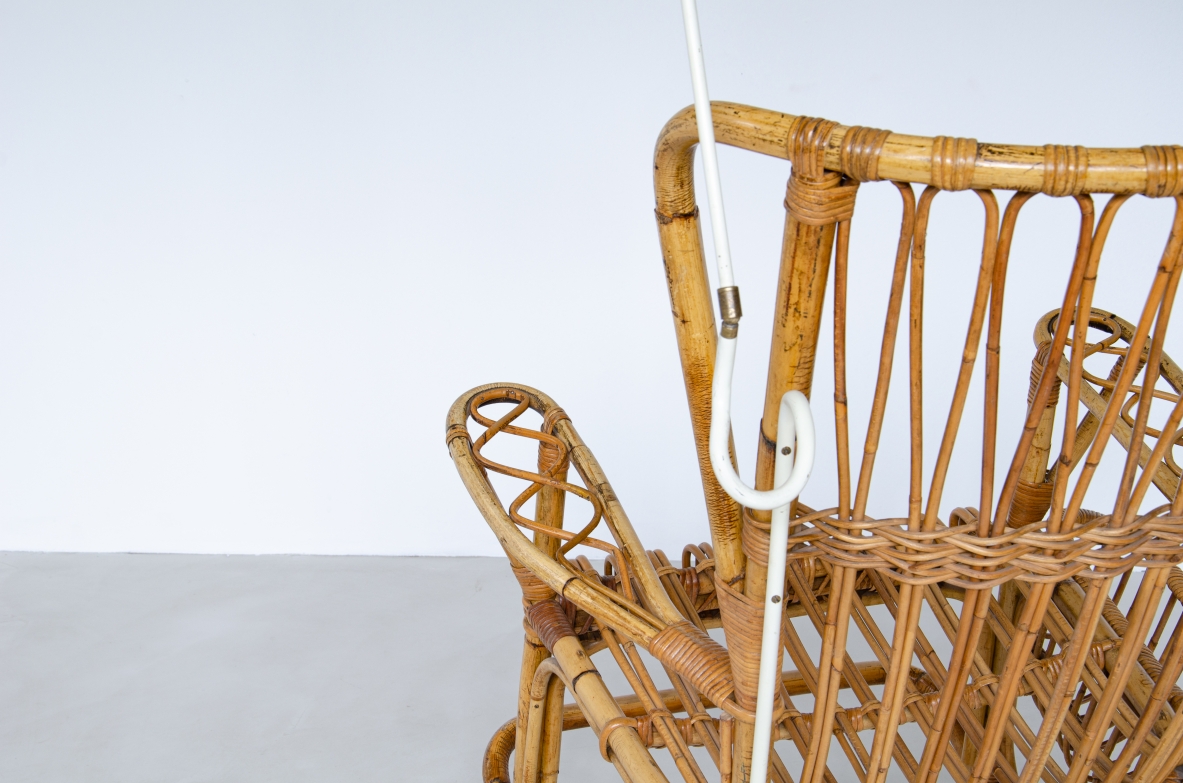 Sedia a dondolo in giunco con portariviste e lampada in metallo laccato. La lampada è applicata alla struttura mediante un tubo in metallo sagomato su misura originale dell epoca.  Prod. Bonacina anni 50'.