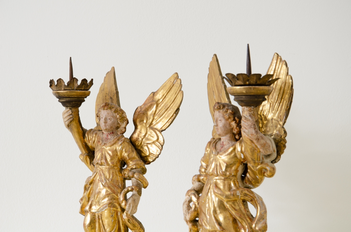 Coppia di angeli in legno laccato e dorato che reggono una cornucopia con corona in metallo dorato.   Italia centrale, epoca Barocco, seconda metà del XVII secolo.