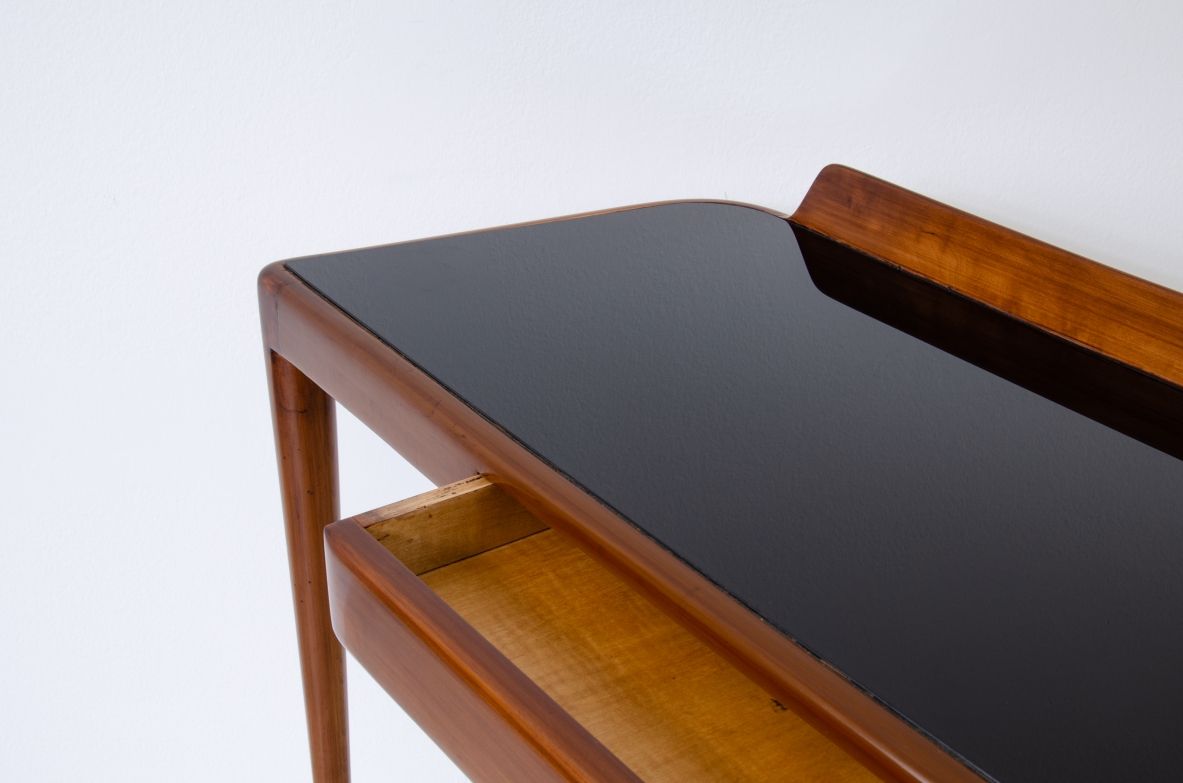 Elegante console con sottili gambe in noce biondo e lunghi puntali in ottone. Cassetto centrale e piano in vetro opaline nero.  Manifattura Italiana 1950ca.