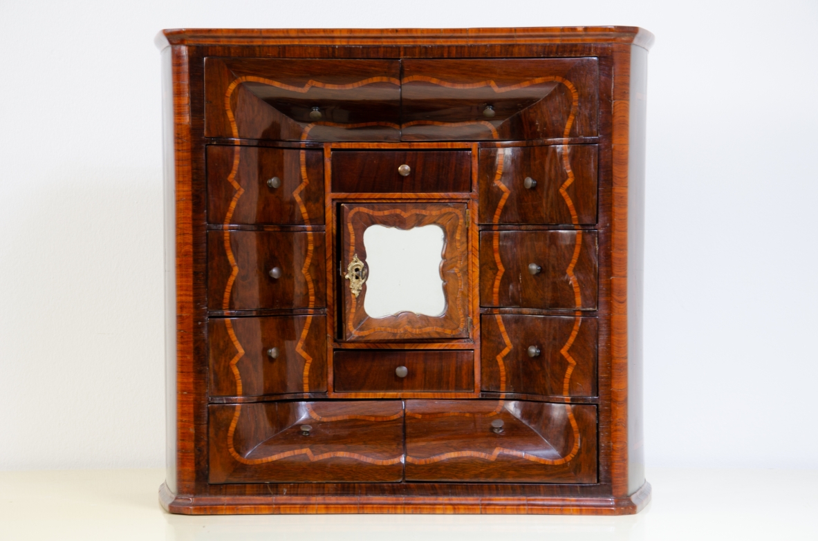 Genoese cabinetry, c. 1750, coin cabinet in violet wood threaded in rose wood with wavy front, central aedicule with shaped door and central mirror.