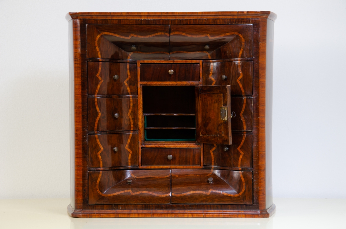 Genoese cabinetry, c. 1750, coin cabinet in violet wood threaded in rose wood with wavy front, central aedicule with shaped door and central mirror.