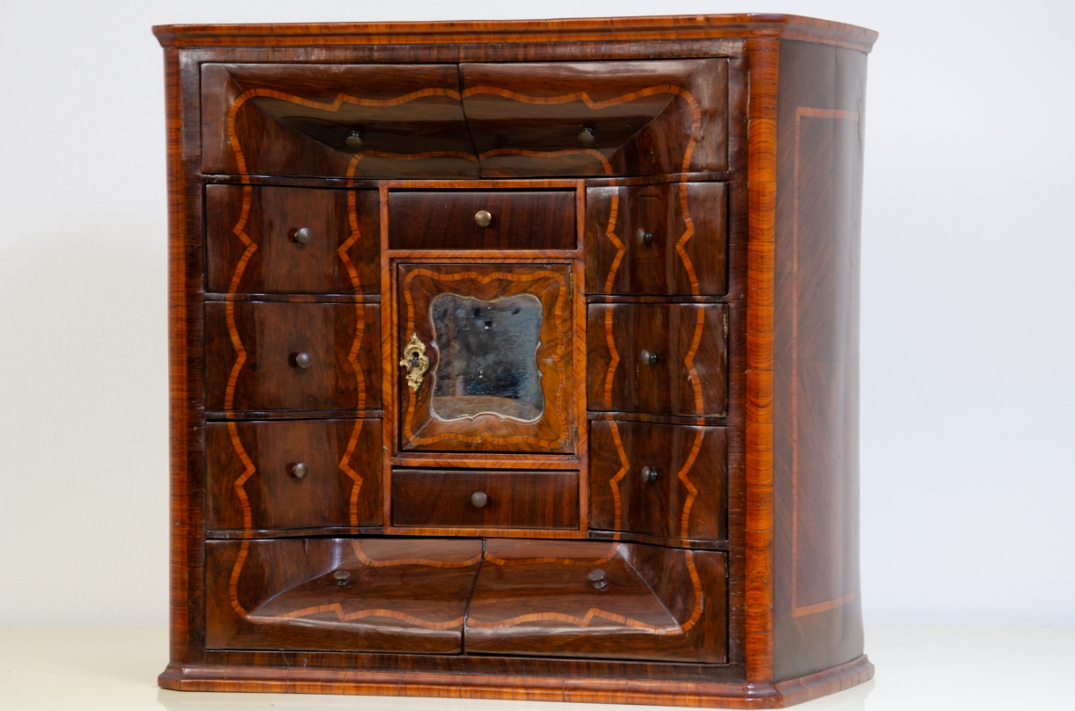 Genoese cabinetry, c. 1750, coin cabinet in violet wood threaded in rose wood with wavy front, central aedicule with shaped door and central mirror.