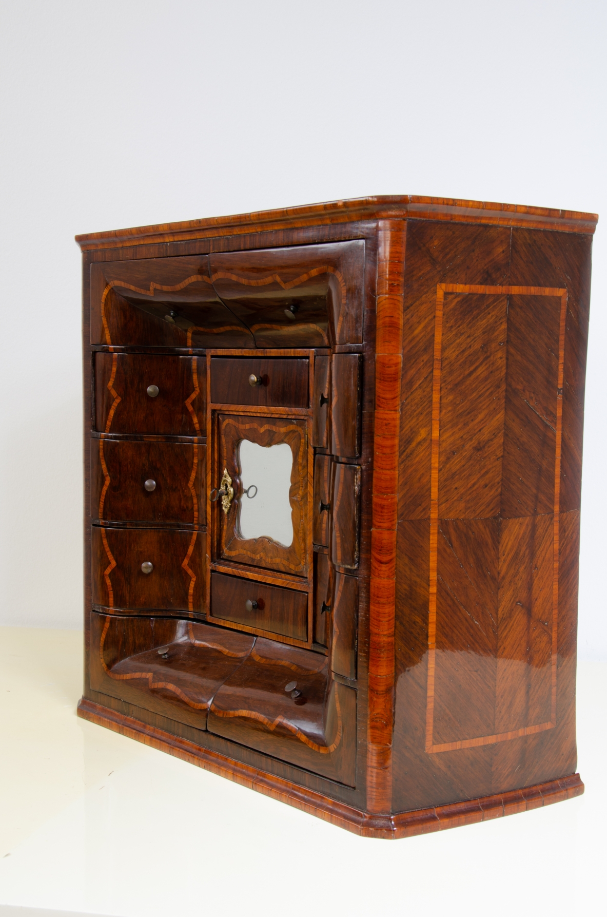 Genoese cabinetry, c. 1750, coin cabinet in violet wood threaded in rose wood with wavy front, central aedicule with shaped door and central mirror.