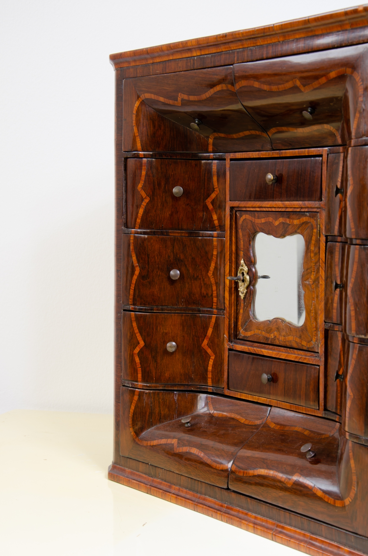 Genoese cabinetry, c. 1750, coin cabinet in violet wood threaded in rose wood with wavy front, central aedicule with shaped door and central mirror.