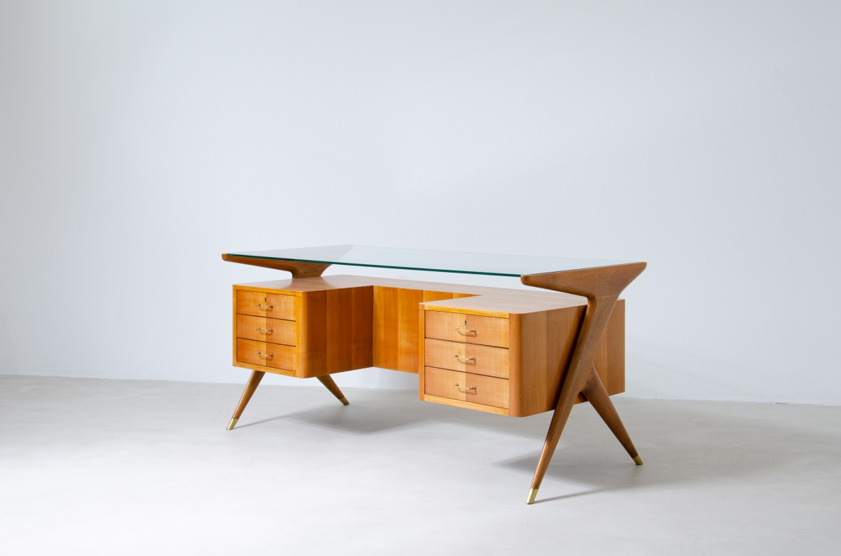 Writing table in blond wood with thick glass top and sculptural side uprights with brass tips.  1950's Italian manufacture.