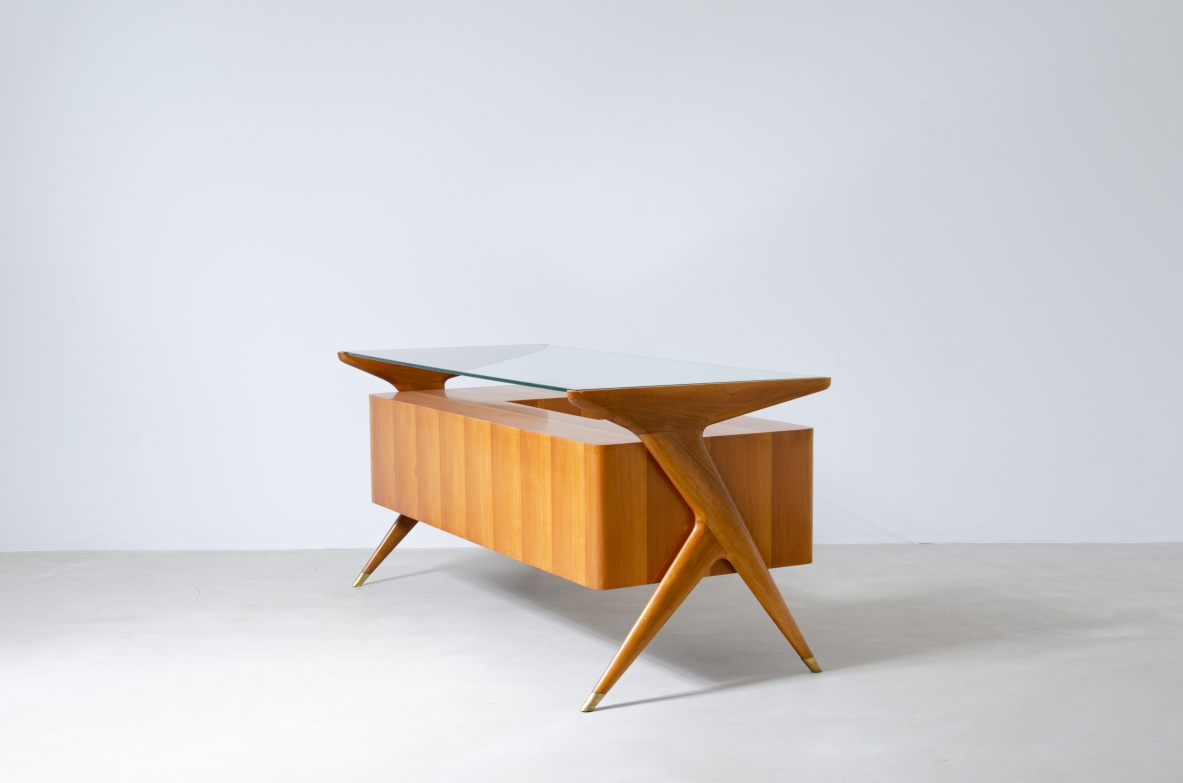 Writing table in blond wood with thick glass top and sculptural side uprights with brass tips.  1950's Italian manufacture.
