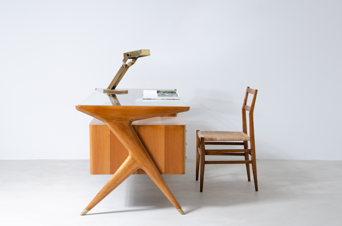 Writing table in blond wood with thick glass top and sculptural side uprights with brass tips.  1950's Italian manufacture.