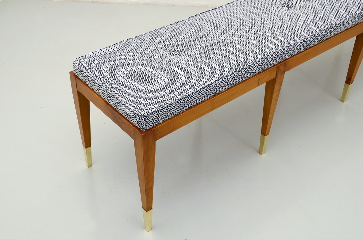 Panca in ciliegio con gambe sottili e puntali in ottone. Produzione Officina Antiquaria.