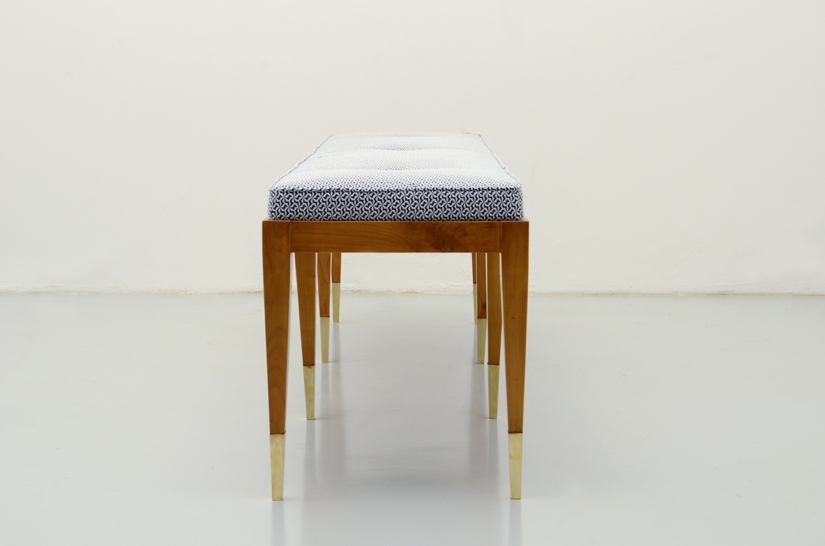 Panca in ciliegio con gambe sottili e puntali in ottone. Produzione Officina Antiquaria.