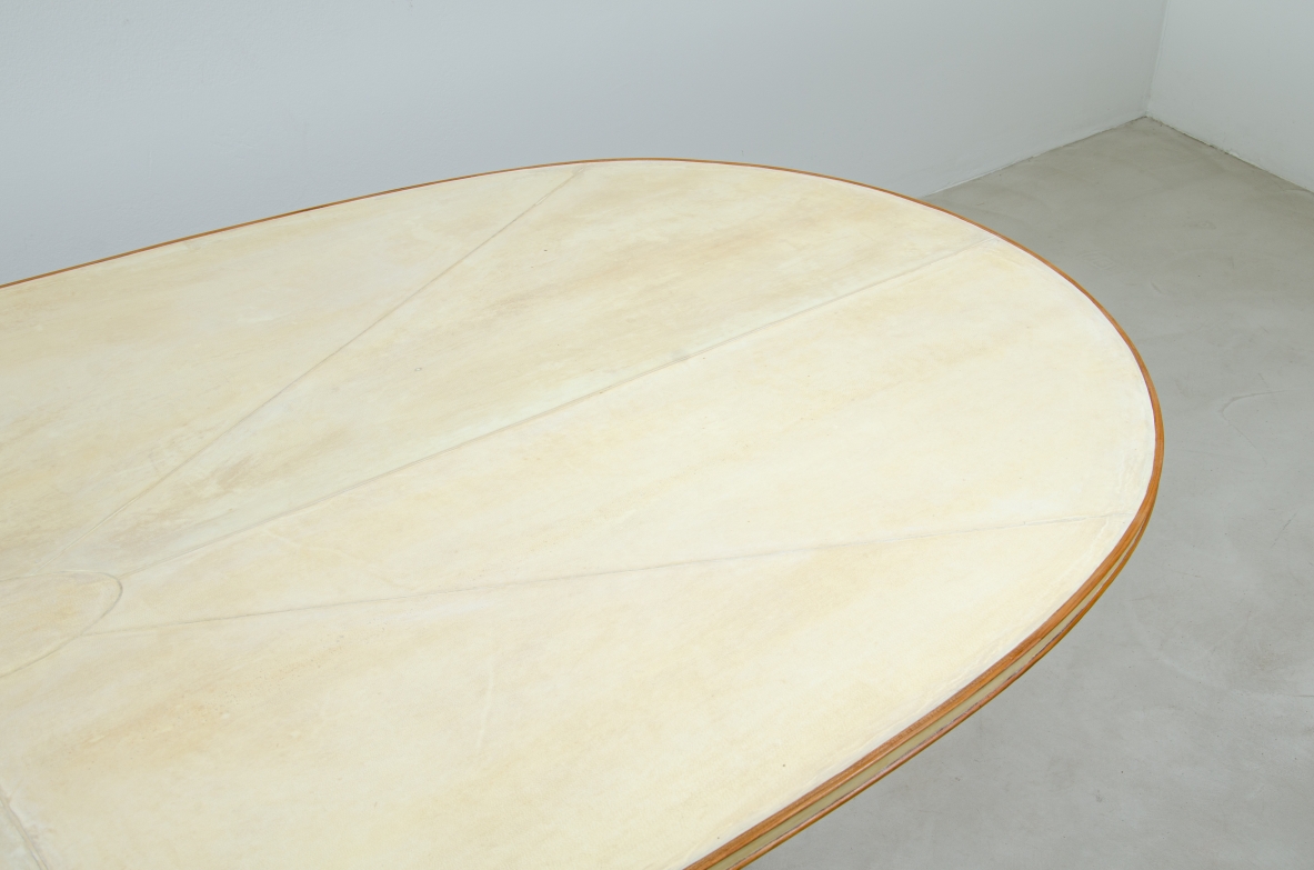 Grande tavolo con elegante struttura in legno biondo e piano rivestito in pergamena.  Manifattura italiana anni 50.