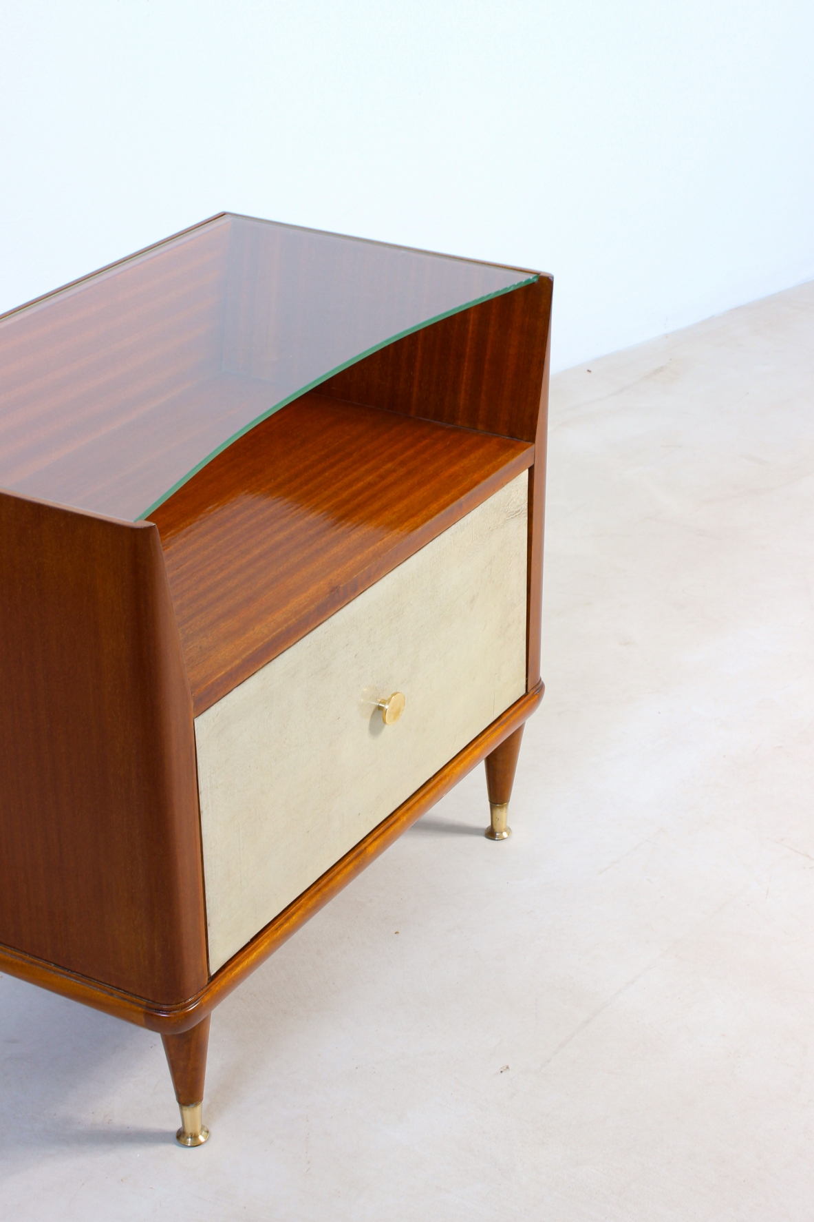 Paolo Buffa (1903 - 1970)  Coppia di comodini con fronte in pergamena e piano in cristallo molato, puntali in ottone e un cassetto all'interno.  Manifattura italiana, 1950ca