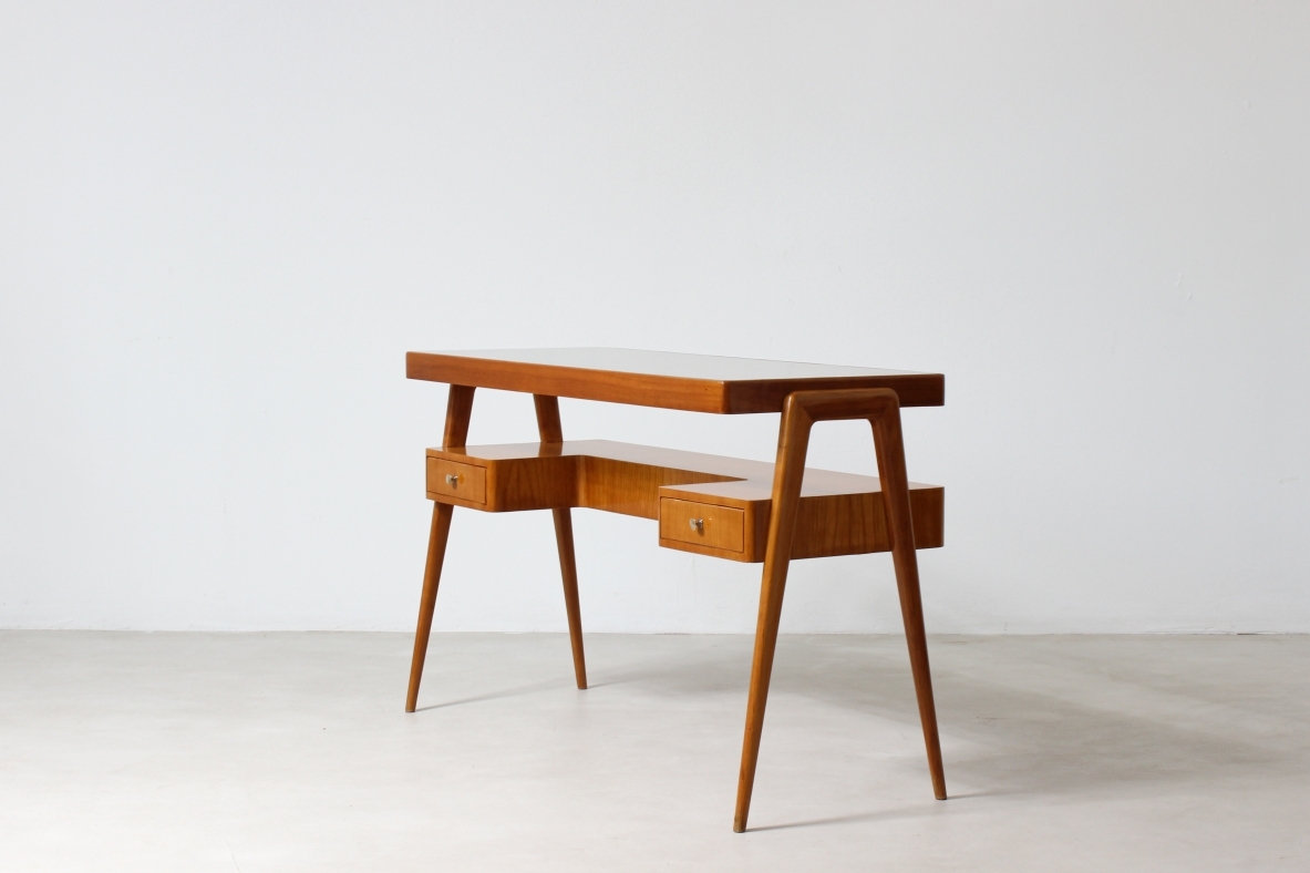 console in legno biondo con piano in vetro e ripiano sagomato con due cassetti sul fronte.