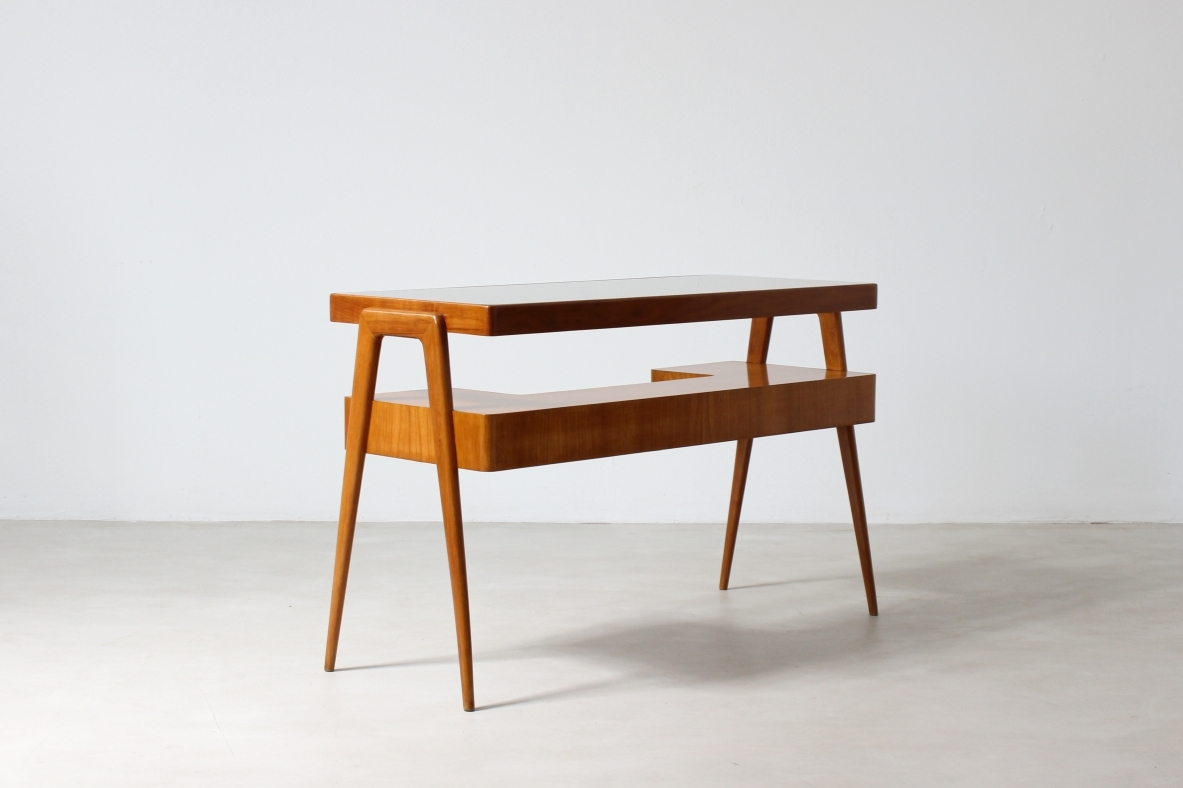 console in legno biondo con piano in vetro e ripiano sagomato con due cassetti sul fronte.