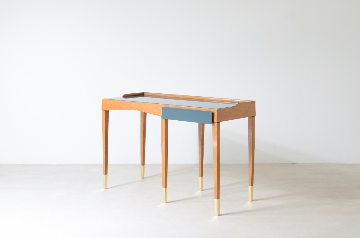Refined oak writing desk with petrol green opaline glass top and backsplash.  Shaped drawer of the same color covered in polypropylene. Long thin legs with brass tips.  Attributed to Gio Ponti, early 1950s manufacture.