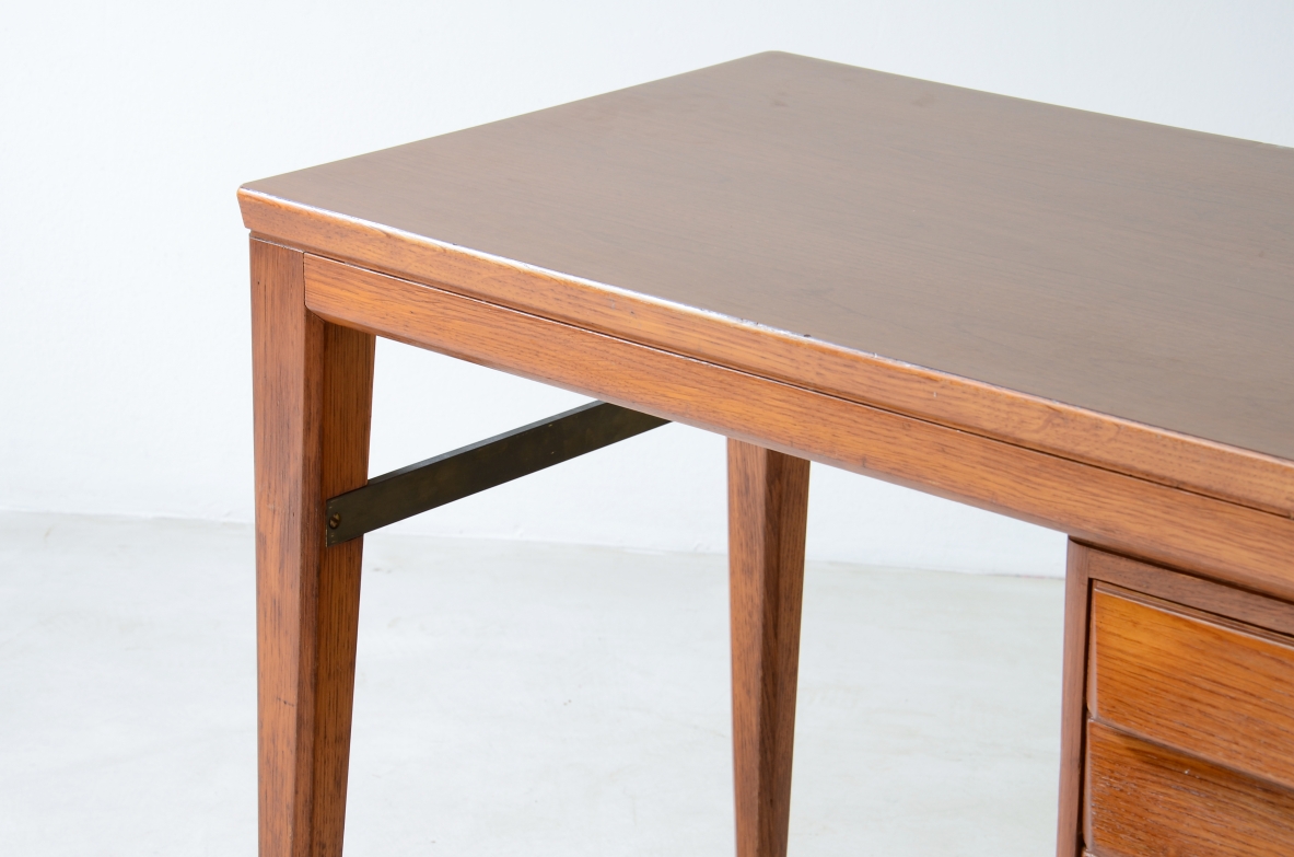 Gio Ponti  Elegante scrivania in rovere disegnata da Gio Ponti per la Banca Nazionale del Lavoro. Gambe leggermente curvate unite da un distanziale in ottone, tre cassetti con fronte sagomato.