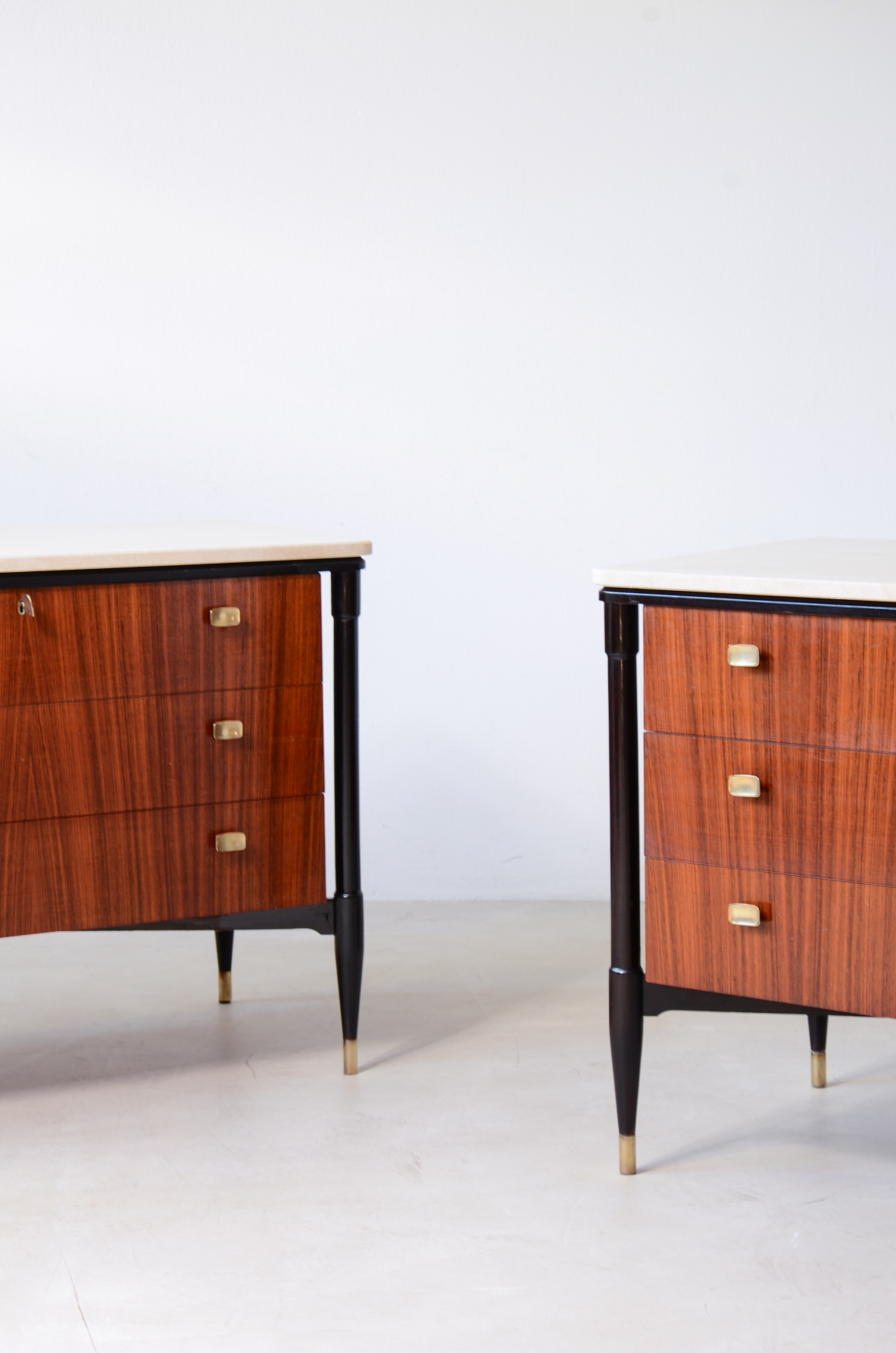 elegant walnut cabinets with travertine tops, three drawers with shaped brass handles. Italian manufacture, circa 1955.