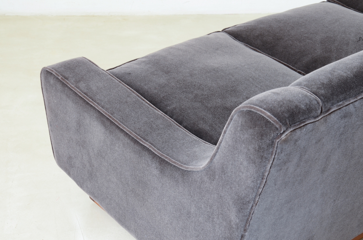 Three-seater sofa with wooden base and padded velvet upholstery.