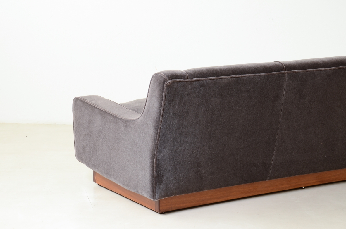 Three-seater sofa with wooden base and padded velvet upholstery.