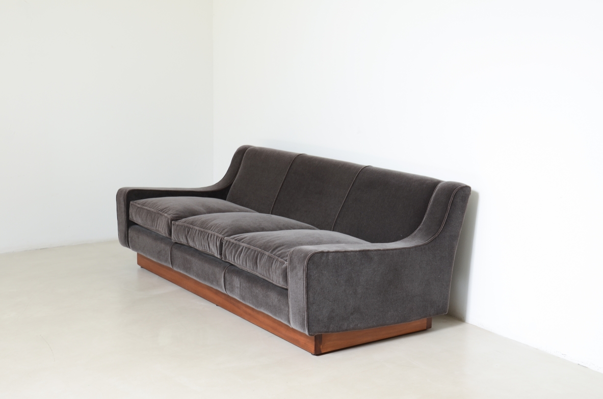 Three-seater sofa with wooden base and padded velvet upholstery.