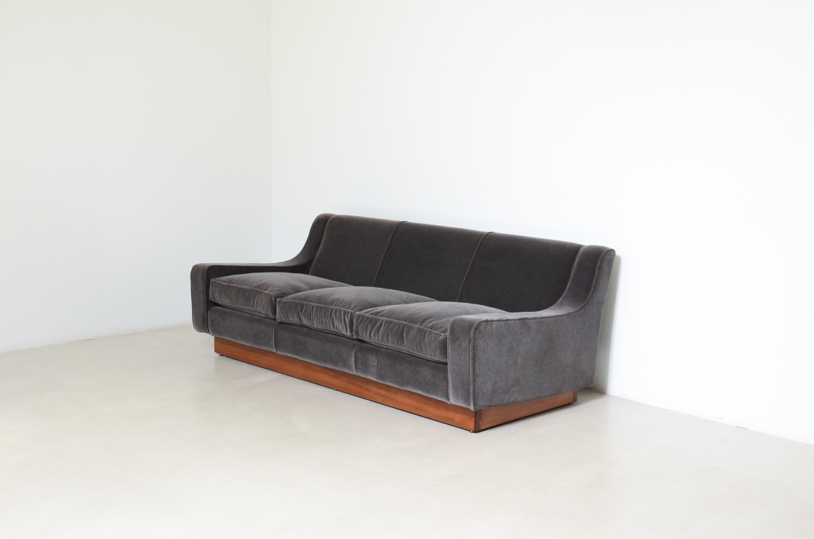 Three-seater sofa with wooden base and padded velvet upholstery.