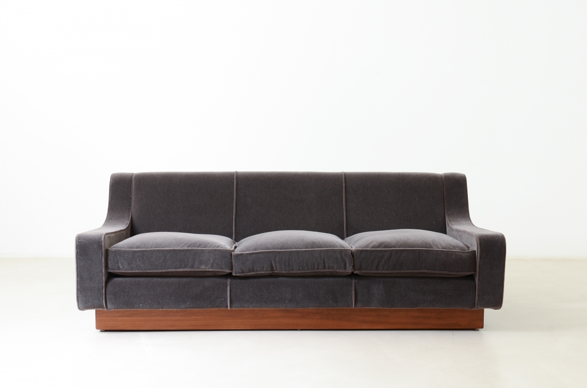 Three-seater sofa with wooden base and padded velvet upholstery.