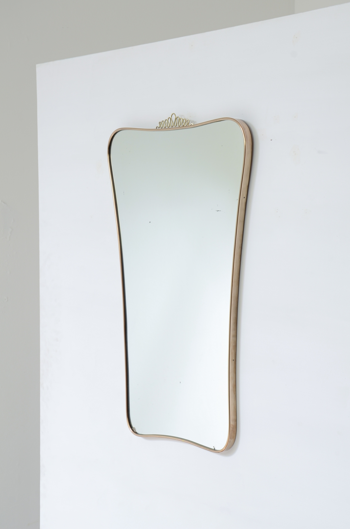 Elegant mirror with shaped brass frame. Attributed to Gio Ponti. Italian manufacture, 1950s.