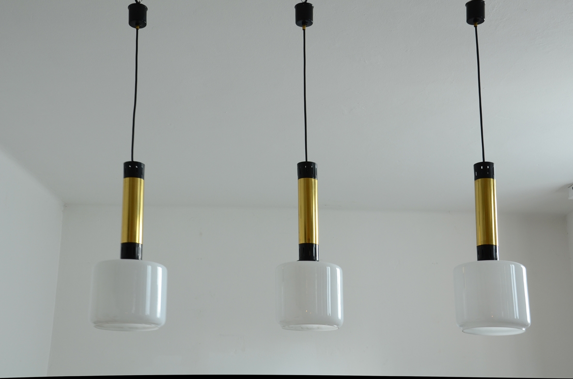 Three elegant Stilnovo suspension lamps with brass structure, lacquered metal and opal glass diffusers.