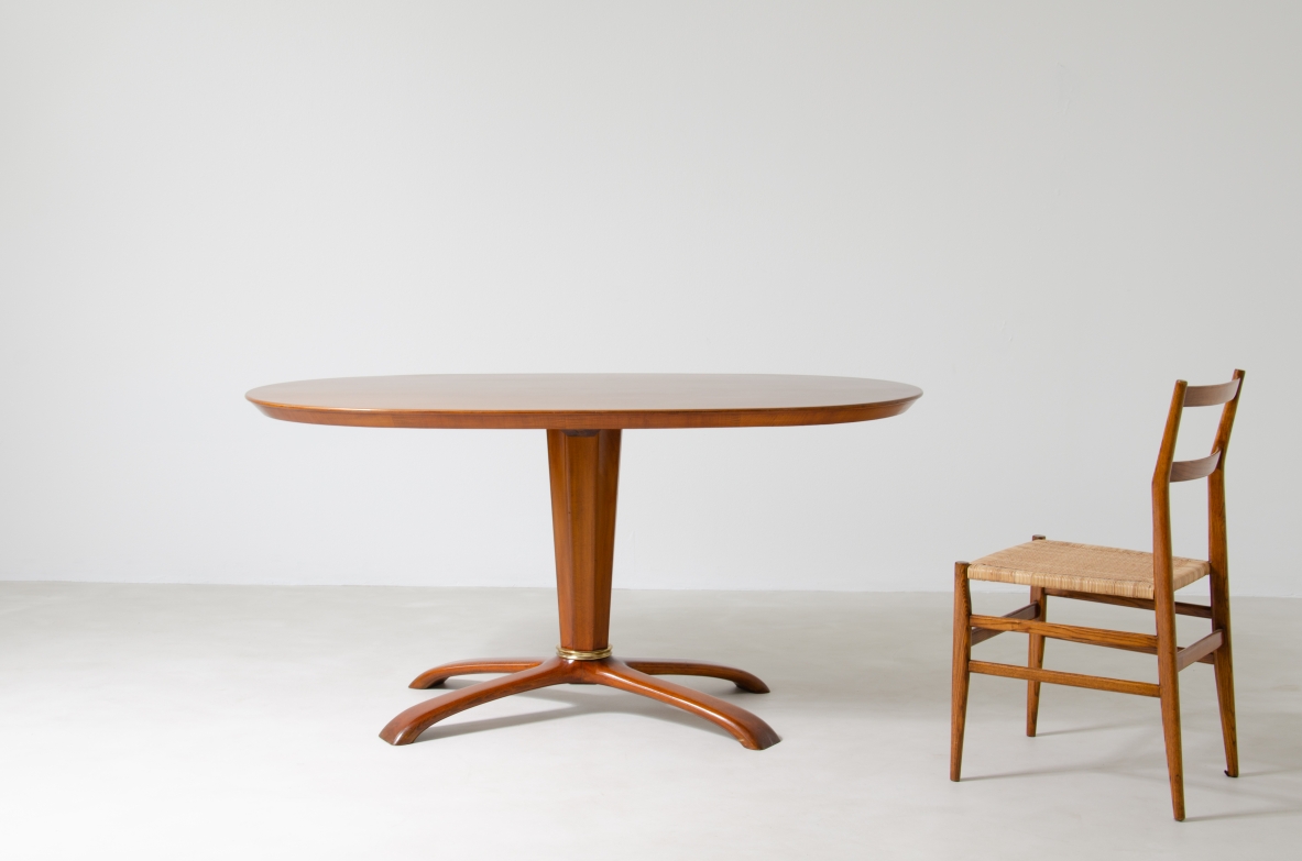 Osvaldo Borsani, tavolo in ciliegio con piano ovale, base a quattro razze e colonna centrale con anello in bronzo, 1950ca.